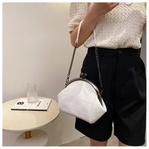 Detailed view of white shell-shaped cross-stitched bag with retro black metal chain