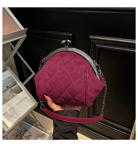 Detail of burgundy quilted suede handbag with vintage silver metal clasp and chain