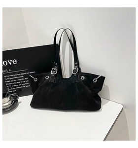 Detailed macro view of black suede tote bag with silver eyelets and metal hardware buckle