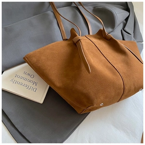 Macro detail of brown faux suede tote bag showing texture, long straps and metal rivets