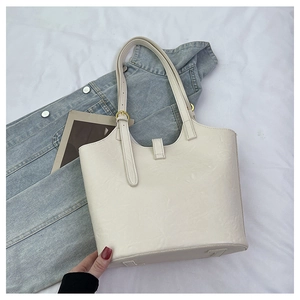 Close-up of cream embossed leather tote bag with gold hardware and adjustable strap
