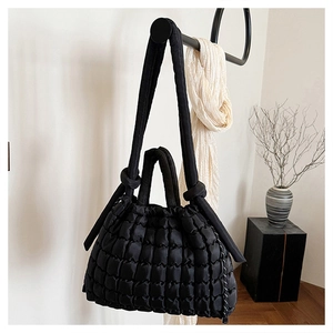 Détail d'un sac matelassé noir avec texture bouffante et bandoulière à nœud élégante
