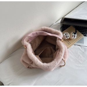 Detail view of pink faux fur bucket bag featuring metal chain and inner pocket