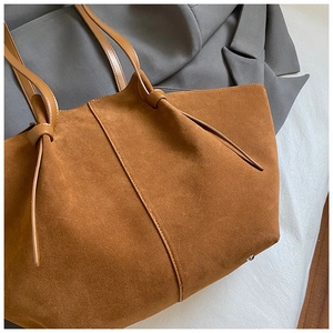 Detailed view of brown suede tote bag with knotted leather handle and minimalist stitching