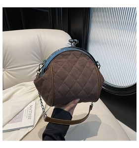 Detail of brown quilted suede shell bag with classic metal clasp and chain strap