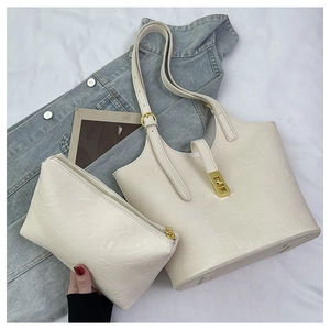 Detail view of large cream embossed tote bag set with matching inner pouch and gold hardware