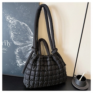 Détail d'un sac cabas noir matelassé avec poignées à nœuds et fermeture à cordon