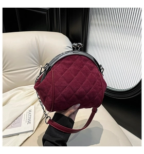 Detail of burgundy quilted suede handbag with vintage silver metal clasp and chain strap