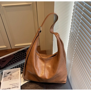 Detailed close-up of brown matte leather hobo bag with adjustable strap and smooth texture