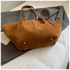 Detail view of large brown suede tote bag featuring protective metal studs at the bottom