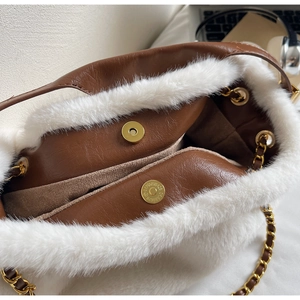 Detail of plush faux fur and brown leather stitching with a golden magnetic clasp