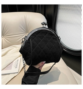 Close-up of black quilted frame bag with silver metal clasp and chain strap detail