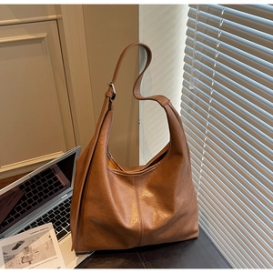 Detail view of brown leather hobo bag with adjustable strap in natural lighting scene