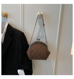 Detail of a brown quilted suede handbag with vintage metal frame hanging on a wall hook