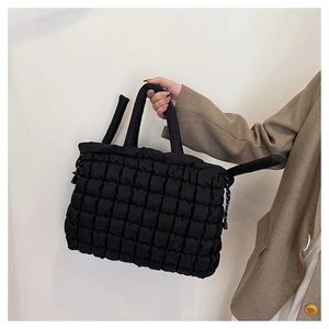 Détail du sac cabas matelassé noir avec texture bulles et poignées souples