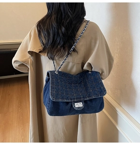 Detailed close-up of dark blue denim quilted bag with silver chain and metal lock