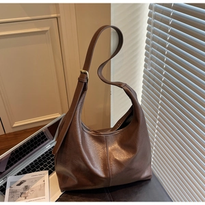 Detail of dark brown hobo bag showing adjustable strap and stitching on leather texture