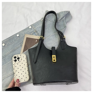 Detail of black tote bag with gold square twist lock and premium leather texture