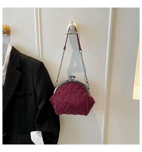 Detail of burgundy velvet frame bag with quilted embroidery and gold chain strap