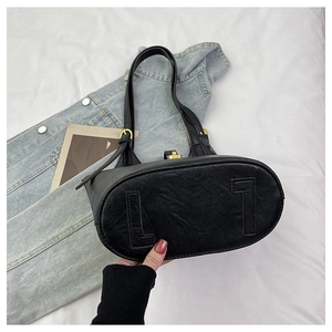 Detail view of the oval bottom structure and premium leather texture of the black tote bag