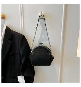 Detail of a black quilted frame bag with a classic gold-tone metal clasp and chain strap
