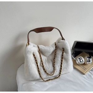 Detailed view of white faux fur tote bag with brown leather handles and gold chain strap