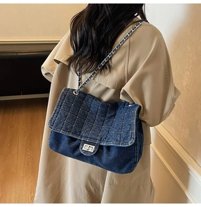 Detail view of denim quilted shoulder bag with silver chain and metal turn-lock closure