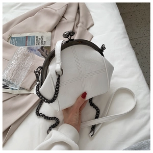 Detail of white shell-shaped bag with cross quilting and dual metallic sphere clasp