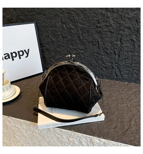 Close-up of black quilted velvet bag with silver metal clasp and leather chain strap