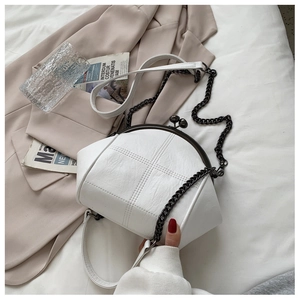 Detail of white quilted shell bag with black metal clasp and chain strap on blazer