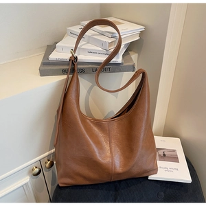 Detail view of the soft brown leather texture and vertical stitching on the hobo tote bag