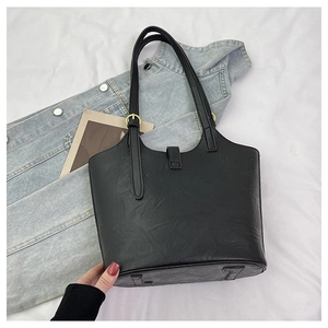 Detail view of the black textured PU leather tote bag with gold metal hardware and buckle