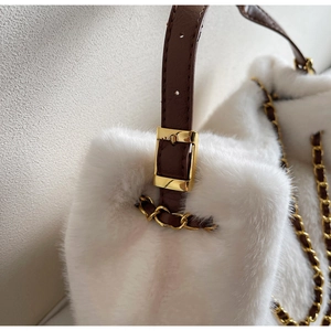 Detail of white faux fur handbag featuring gold buckle and brown leather chain strap