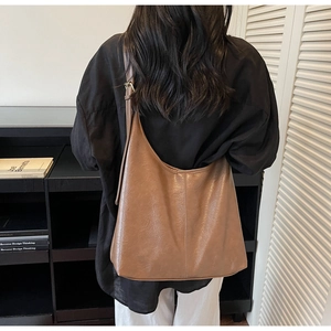Detail of soft brown leather tote bag with vintage texture and adjustable strap on model