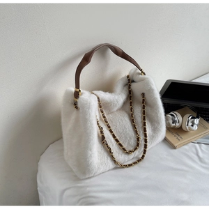 Detail of white faux fur tote bag showing plush texture, leather handles, and gold chain strap
