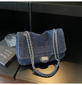 Detailed shot of quilted blue denim texture and silver chain strap on the handbag