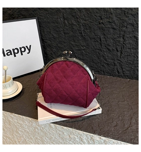Detailed close-up of burgundy quilted frame bag with metal clasp on vintage books