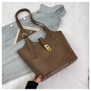 Detail of dark brown leather tote bag showing golden rectangular buckle and fine texture