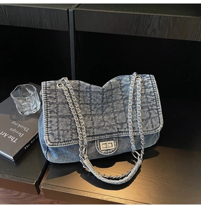Close-up of blue washed denim crossbody bag with quilted grid texture and silver chain