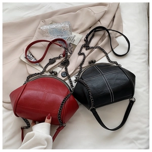 Detail shot of solid red and black shell bags with metal clasps and chain straps