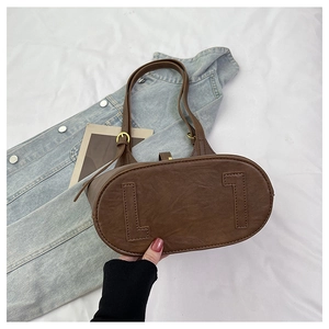 Detail view of the oval base on a coffee brown bucket bag with reinforced leather accents