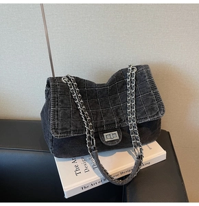 Detail of vintage denim bag with quilted stitching, metal chain, and silver turn-lock