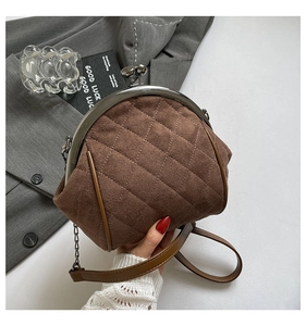 Detail of dark brown quilted suede bag with classic metal kiss-lock closure and chain strap