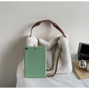 White plush handbag with brown leather handle and gold chain next to a green tablet
