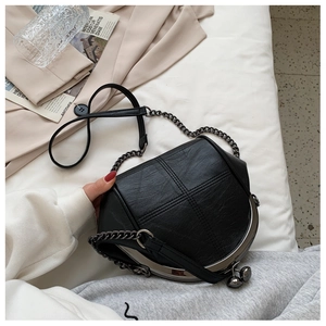 Detail of black PU leather shell bag with quilted stitching and metal frame clasp