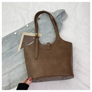 Detail of a brown PU leather tote bag showing fine stitching and golden buckle accents
