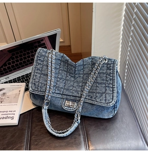 Close-up of quilted blue denim bag showing silver rotary lock and chain strap details