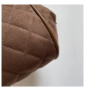 Macro detail of brown quilted suede fabric and leather trim on a vintage chain bag