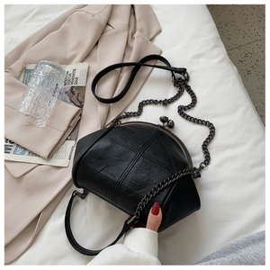 Top view of a black vintage frame bag with litchi texture and chain strap on a blazer