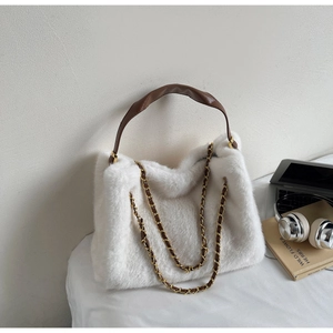 Detail of white faux fur tote bag with brown leather handles and golden chain strap